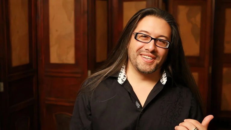 John Romero confirma que su shooter descartado por Xbox tiene nueva editora y ha sido rediseñado tras recontratar personal John Romero, cocreador de Doom y Quake y cofundador de id Software, confirmó que el proyecto de disparos (shooter) no anunciado de Romero Games —el cual perdió el respaldo de Xbox anteriormente— cuenta ahora con una nueva editora. Además, el estudio ha vuelto a contratar a parte de su personal para trabajar en una versión completamente rediseñada del título. Durante una entrevista con el medio VGC (firmada por el periodista Chris Scullion) en el marco de Gamescom Asia, el diseñador de títulos clásicos como Wolfenstein 3D explicó cómo el estudio logró salvar la producción tras perder su financiamiento anterior. Del recorte de Microsoft a un acuerdo con libertad creativa total El proyecto atravesó una crisis cuando una editora no especificada en un primer momento —y posteriormente identificada como Microsoft— retiró su acuerdo de publicación como parte de una ola de despidos dentro de la corporación. En aquel momento, varios empleados señalaron que todo el estudio había sido despedido, aunque Romero Games negó el cierre definitivo de la empresa y mantuvo la esperanza de encontrar otro socio comercial. Según detalló Romero, el estudio intentó mantener a toda la plantilla el mayor tiempo posible mientras buscaba financiamiento para terminar el juego original. Sin embargo, a medida que pasaba el tiempo y el personal se marchaba, resultó inviable sostener esa estructura, por lo que aplicaron recortes hasta pasar de 110 personas a solo cinco. El punto clave para la supervivencia del proyecto fue que Romero Games posee el 100 % de los derechos: el nombre, la propiedad intelectual (IP), el arte, los gráficos y el código. Con esos recursos asegurados, Romero contactó a un conocido de la industria y cerró un nuevo trato de publicación. Aunque afirmó que no puede revelar el nombre de la nueva editora ni la fecha del anuncio oficial, destacó que este socio no impone exigencias sobre el contenido: "La editora con la que estamos ahora mismo tiene cero objetivos creativos para este juego. Su postura es: 'haz lo que quieras, nosotros lo publicamos, no te vamos a decir qué hacer'. Ese es el trato perfecto". Un rediseño completo utilizando los recursos originales Lejos de continuar exactamente con la misma producción masiva, Romero aclaró que la versión original planeada para un equipo de 110 personas no podía terminarse con una plantilla reducida debido a su alta complejidad. Por ello, optó por diseñar un título completamente diferente desde la base, pero ajustado a la escala actual y reutilizando gran parte del trabajo previo. El equipo trasladó código común del género shooter, arte, gráficos, personajes y armas al nuevo proyecto, lo que les dio una ventaja inicial importante. Si bien la base de disparos se mantiene, el creativo aseguró que todo lo que rodea al juego es nuevo. Regreso de líderes clave y trabajo directo en Unreal Editor Tras asegurar el financiamiento, Romero Games recontrató a 10 personas, quienes se desempeñaban como los líderes de los diferentes subequipos que tenía el estudio anteriormente. Sumados a los cinco integrantes que habían permanecido, el equipo actual ronda entre los 15 y 16 trabajadores, una cifra en la que planean mantenerse. Esta estructura horizontal, compuesta únicamente por líderes de área que conocen sus tareas sin necesidad de supervisión constante, le permite a Romero trabajar directamente en el día a día del desarrollo. El diseñador comentó que prefiere evitar las reuniones de todo el día propias de los equipos de más de 100 personas, y que actualmente toma cada decisión trabajando de forma manual dentro de Unreal Editor mientras dirige al resto del grupo. Asimismo, Romero descartó volver a trabajar con una gran editora en el futuro. Señaló que los equipos pequeños permiten cambiar el rumbo del desarrollo en cuestión de horas si es necesario y eliminan la necesidad de contar con múltiples productores: "No me gusta tener un montón de productores, porque eso significa tener un montón de gente, y ahora mismo no hay ningún productor. Es genial. No lo necesitamos, todos somos líderes, sabemos cómo funciona, no es complejo. Estamos en el tamaño correcto. Todavía no necesitamos un productor y no vamos a contratar uno. Supongo que en el momento en que necesitas un productor, ya eres demasiado grande". Por ahora, el nuevo shooter de Romero Games avanza internamente bajo este esquema reducido, sin ventana de lanzamiento ni plataformas confirmadas.