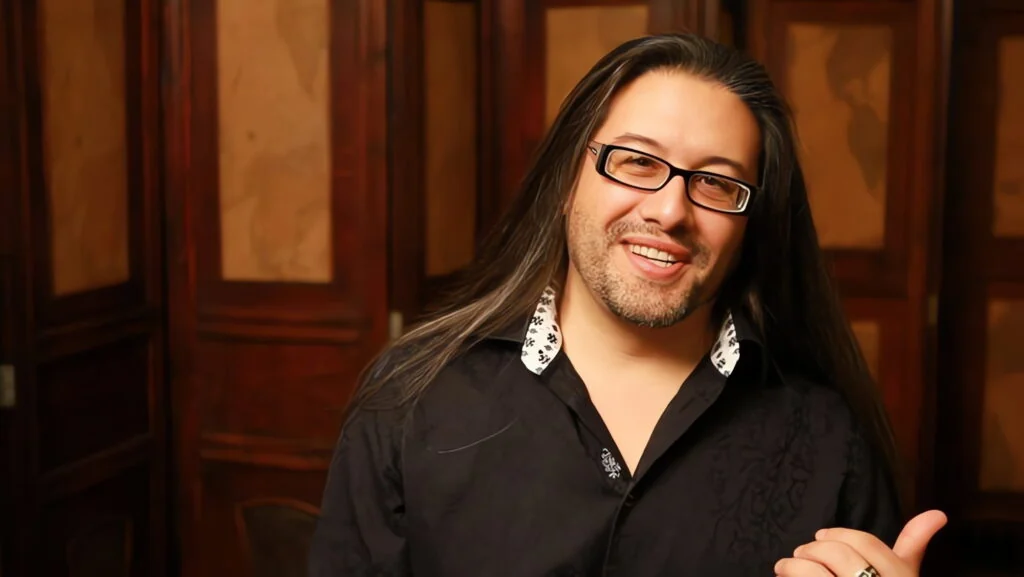 John Romero confirma que su shooter descartado por Xbox tiene nueva editora y ha sido rediseñado tras recontratar personal
John Romero, cocreador de Doom y Quake y cofundador de id Software, confirmó que el proyecto de disparos (shooter) no anunciado de Romero Games —el cual perdió el respaldo de Xbox anteriormente— cuenta ahora con una nueva editora. Además, el estudio ha vuelto a contratar a parte de su personal para trabajar en una versión completamente rediseñada del título.

Durante una entrevista con el medio VGC (firmada por el periodista Chris Scullion) en el marco de Gamescom Asia, el diseñador de títulos clásicos como Wolfenstein 3D explicó cómo el estudio logró salvar la producción tras perder su financiamiento anterior.

Del recorte de Microsoft a un acuerdo con libertad creativa total
El proyecto atravesó una crisis cuando una editora no especificada en un primer momento —y posteriormente identificada como Microsoft— retiró su acuerdo de publicación como parte de una ola de despidos dentro de la corporación. En aquel momento, varios empleados señalaron que todo el estudio había sido despedido, aunque Romero Games negó el cierre definitivo de la empresa y mantuvo la esperanza de encontrar otro socio comercial.

Según detalló Romero, el estudio intentó mantener a toda la plantilla el mayor tiempo posible mientras buscaba financiamiento para terminar el juego original. Sin embargo, a medida que pasaba el tiempo y el personal se marchaba, resultó inviable sostener esa estructura, por lo que aplicaron recortes hasta pasar de 110 personas a solo cinco.

El punto clave para la supervivencia del proyecto fue que Romero Games posee el 100 % de los derechos: el nombre, la propiedad intelectual (IP), el arte, los gráficos y el código. Con esos recursos asegurados, Romero contactó a un conocido de la industria y cerró un nuevo trato de publicación. Aunque afirmó que no puede revelar el nombre de la nueva editora ni la fecha del anuncio oficial, destacó que este socio no impone exigencias sobre el contenido:

"La editora con la que estamos ahora mismo tiene cero objetivos creativos para este juego. Su postura es: 'haz lo que quieras, nosotros lo publicamos, no te vamos a decir qué hacer'. Ese es el trato perfecto".

Un rediseño completo utilizando los recursos originales
Lejos de continuar exactamente con la misma producción masiva, Romero aclaró que la versión original planeada para un equipo de 110 personas no podía terminarse con una plantilla reducida debido a su alta complejidad. Por ello, optó por diseñar un título completamente diferente desde la base, pero ajustado a la escala actual y reutilizando gran parte del trabajo previo.

El equipo trasladó código común del género shooter, arte, gráficos, personajes y armas al nuevo proyecto, lo que les dio una ventaja inicial importante. Si bien la base de disparos se mantiene, el creativo aseguró que todo lo que rodea al juego es nuevo.

Regreso de líderes clave y trabajo directo en Unreal Editor
Tras asegurar el financiamiento, Romero Games recontrató a 10 personas, quienes se desempeñaban como los líderes de los diferentes subequipos que tenía el estudio anteriormente. Sumados a los cinco integrantes que habían permanecido, el equipo actual ronda entre los 15 y 16 trabajadores, una cifra en la que planean mantenerse.

Esta estructura horizontal, compuesta únicamente por líderes de área que conocen sus tareas sin necesidad de supervisión constante, le permite a Romero trabajar directamente en el día a día del desarrollo. El diseñador comentó que prefiere evitar las reuniones de todo el día propias de los equipos de más de 100 personas, y que actualmente toma cada decisión trabajando de forma manual dentro de Unreal Editor mientras dirige al resto del grupo.

Asimismo, Romero descartó volver a trabajar con una gran editora en el futuro. Señaló que los equipos pequeños permiten cambiar el rumbo del desarrollo en cuestión de horas si es necesario y eliminan la necesidad de contar con múltiples productores:

"No me gusta tener un montón de productores, porque eso significa tener un montón de gente, y ahora mismo no hay ningún productor. Es genial. No lo necesitamos, todos somos líderes, sabemos cómo funciona, no es complejo. Estamos en el tamaño correcto. Todavía no necesitamos un productor y no vamos a contratar uno. Supongo que en el momento en que necesitas un productor, ya eres demasiado grande".

Por ahora, el nuevo shooter de Romero Games avanza internamente bajo este esquema reducido, sin ventana de lanzamiento ni plataformas confirmadas.John Romero confirma que su shooter descartado por Xbox tiene nueva editora y ha sido rediseñado tras recontratar personal
John Romero, cocreador de Doom y Quake y cofundador de id Software, confirmó que el proyecto de disparos (shooter) no anunciado de Romero Games —el cual perdió el respaldo de Xbox anteriormente— cuenta ahora con una nueva editora. Además, el estudio ha vuelto a contratar a parte de su personal para trabajar en una versión completamente rediseñada del título.

Durante una entrevista con el medio VGC (firmada por el periodista Chris Scullion) en el marco de Gamescom Asia, el diseñador de títulos clásicos como Wolfenstein 3D explicó cómo el estudio logró salvar la producción tras perder su financiamiento anterior.

Del recorte de Microsoft a un acuerdo con libertad creativa total
El proyecto atravesó una crisis cuando una editora no especificada en un primer momento —y posteriormente identificada como Microsoft— retiró su acuerdo de publicación como parte de una ola de despidos dentro de la corporación. En aquel momento, varios empleados señalaron que todo el estudio había sido despedido, aunque Romero Games negó el cierre definitivo de la empresa y mantuvo la esperanza de encontrar otro socio comercial.

Según detalló Romero, el estudio intentó mantener a toda la plantilla el mayor tiempo posible mientras buscaba financiamiento para terminar el juego original. Sin embargo, a medida que pasaba el tiempo y el personal se marchaba, resultó inviable sostener esa estructura, por lo que aplicaron recortes hasta pasar de 110 personas a solo cinco.

El punto clave para la supervivencia del proyecto fue que Romero Games posee el 100 % de los derechos: el nombre, la propiedad intelectual (IP), el arte, los gráficos y el código. Con esos recursos asegurados, Romero contactó a un conocido de la industria y cerró un nuevo trato de publicación. Aunque afirmó que no puede revelar el nombre de la nueva editora ni la fecha del anuncio oficial, destacó que este socio no impone exigencias sobre el contenido:

"La editora con la que estamos ahora mismo tiene cero objetivos creativos para este juego. Su postura es: 'haz lo que quieras, nosotros lo publicamos, no te vamos a decir qué hacer'. Ese es el trato perfecto".

Un rediseño completo utilizando los recursos originales
Lejos de continuar exactamente con la misma producción masiva, Romero aclaró que la versión original planeada para un equipo de 110 personas no podía terminarse con una plantilla reducida debido a su alta complejidad. Por ello, optó por diseñar un título completamente diferente desde la base, pero ajustado a la escala actual y reutilizando gran parte del trabajo previo.

El equipo trasladó código común del género shooter, arte, gráficos, personajes y armas al nuevo proyecto, lo que les dio una ventaja inicial importante. Si bien la base de disparos se mantiene, el creativo aseguró que todo lo que rodea al juego es nuevo.

Regreso de líderes clave y trabajo directo en Unreal Editor
Tras asegurar el financiamiento, Romero Games recontrató a 10 personas, quienes se desempeñaban como los líderes de los diferentes subequipos que tenía el estudio anteriormente. Sumados a los cinco integrantes que habían permanecido, el equipo actual ronda entre los 15 y 16 trabajadores, una cifra en la que planean mantenerse.

Esta estructura horizontal, compuesta únicamente por líderes de área que conocen sus tareas sin necesidad de supervisión constante, le permite a Romero trabajar directamente en el día a día del desarrollo. El diseñador comentó que prefiere evitar las reuniones de todo el día propias de los equipos de más de 100 personas, y que actualmente toma cada decisión trabajando de forma manual dentro de Unreal Editor mientras dirige al resto del grupo.

Asimismo, Romero descartó volver a trabajar con una gran editora en el futuro. Señaló que los equipos pequeños permiten cambiar el rumbo del desarrollo en cuestión de horas si es necesario y eliminan la necesidad de contar con múltiples productores:

"No me gusta tener un montón de productores, porque eso significa tener un montón de gente, y ahora mismo no hay ningún productor. Es genial. No lo necesitamos, todos somos líderes, sabemos cómo funciona, no es complejo. Estamos en el tamaño correcto. Todavía no necesitamos un productor y no vamos a contratar uno. Supongo que en el momento en que necesitas un productor, ya eres demasiado grande".

Por ahora, el nuevo shooter de Romero Games avanza internamente bajo este esquema reducido, sin ventana de lanzamiento ni plataformas confirmadas.